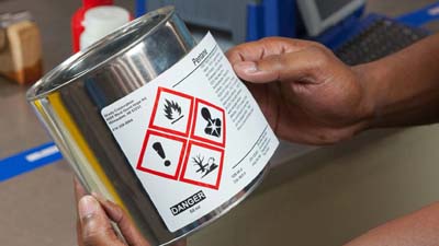 A preprinted hazardous material label being applied to a can.