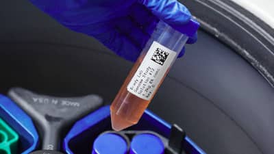 A label on a test tube being inserted into a centrifuge.