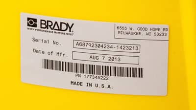 A Brady glossy metallised polyester label applied to the curved surface of a larger cannister.