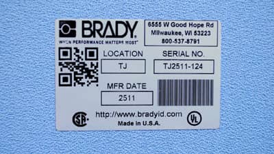 A metallised glossy rating plate label applied to a textured surface.