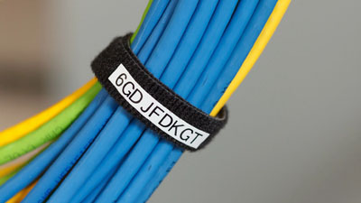 A bundle of blue, green and yellow cables wrapped with a black Velcro strap which has a white label.