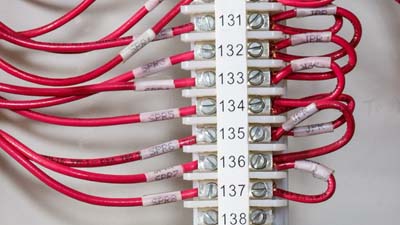 A series of red wires within a terminal block identified with a white terminal block label.