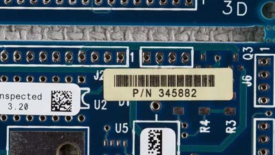 A white barcode label on a blue circuit board.