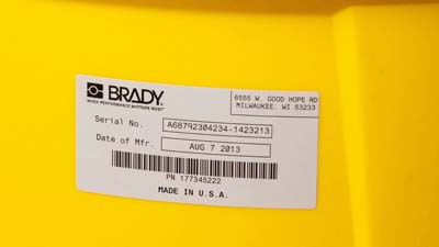 A Brady glossy metallised polyester label applied to the curved surface of a larger cannister.
