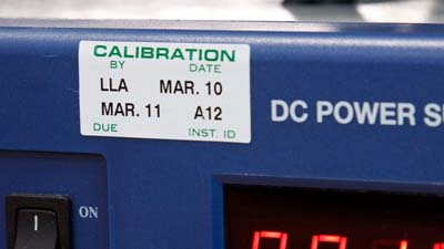 A Brady preprinted calibration label applied to a DC power supply to indicate the last date it was calibrated.
