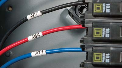 Three Brady high-temp, flame-retardent wrap around labels applied to electrical wires connect to circuit breakers.