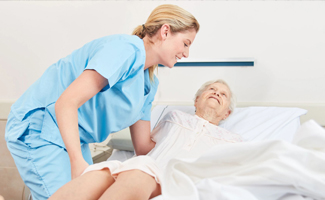 nurse helping an elderly person onto their medical bed